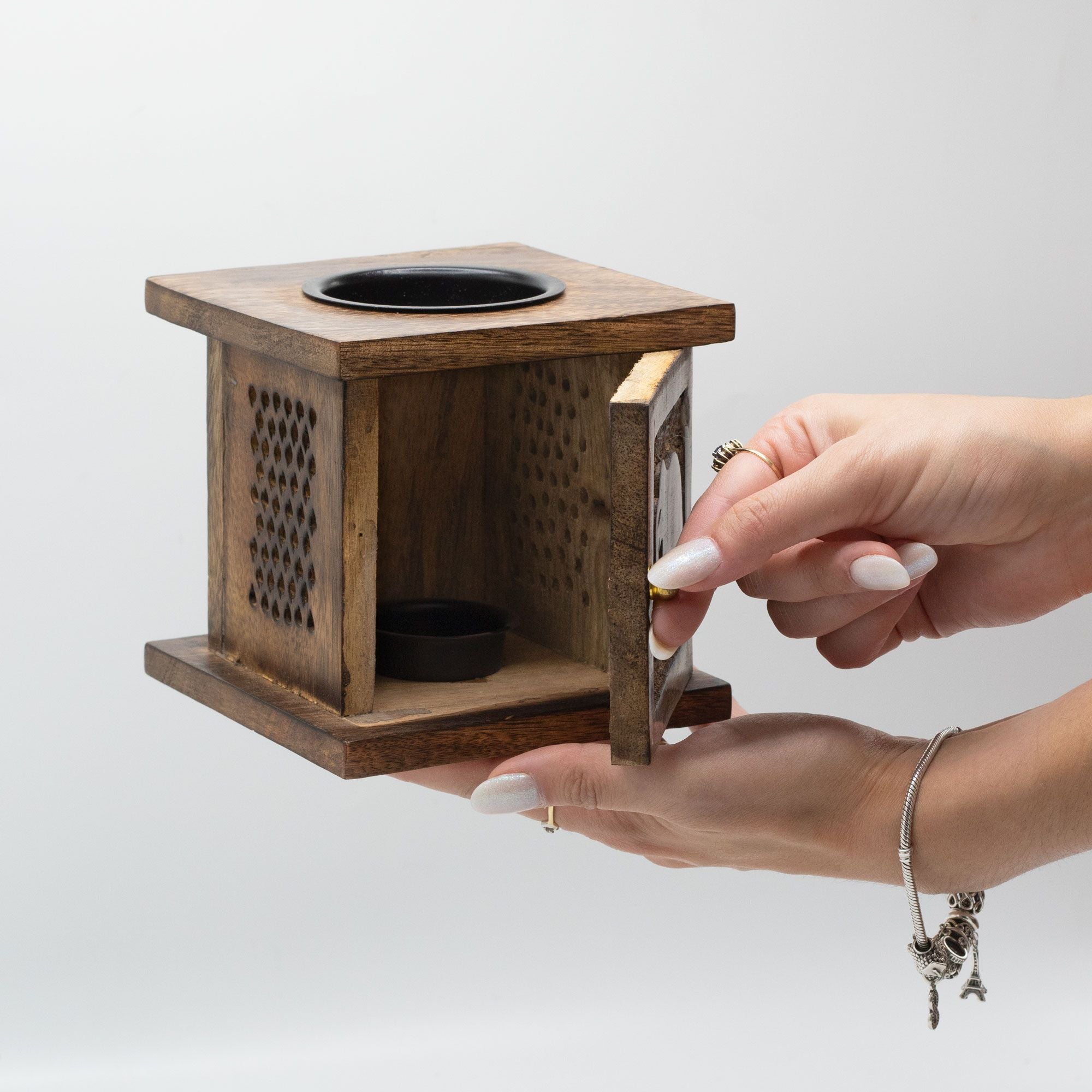 Wooden square box with a hand opening it on a light gray background