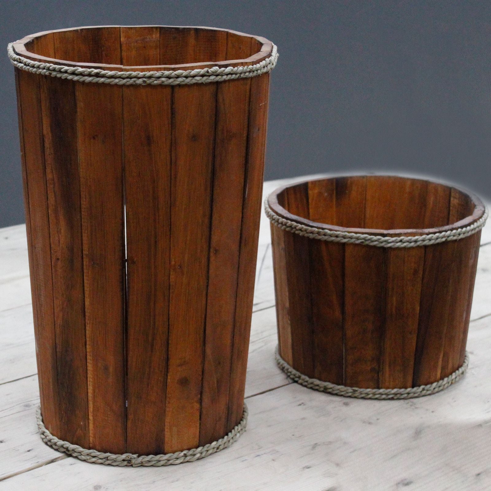 Two wooden waste bins with rope handles on a light wooden surface.
