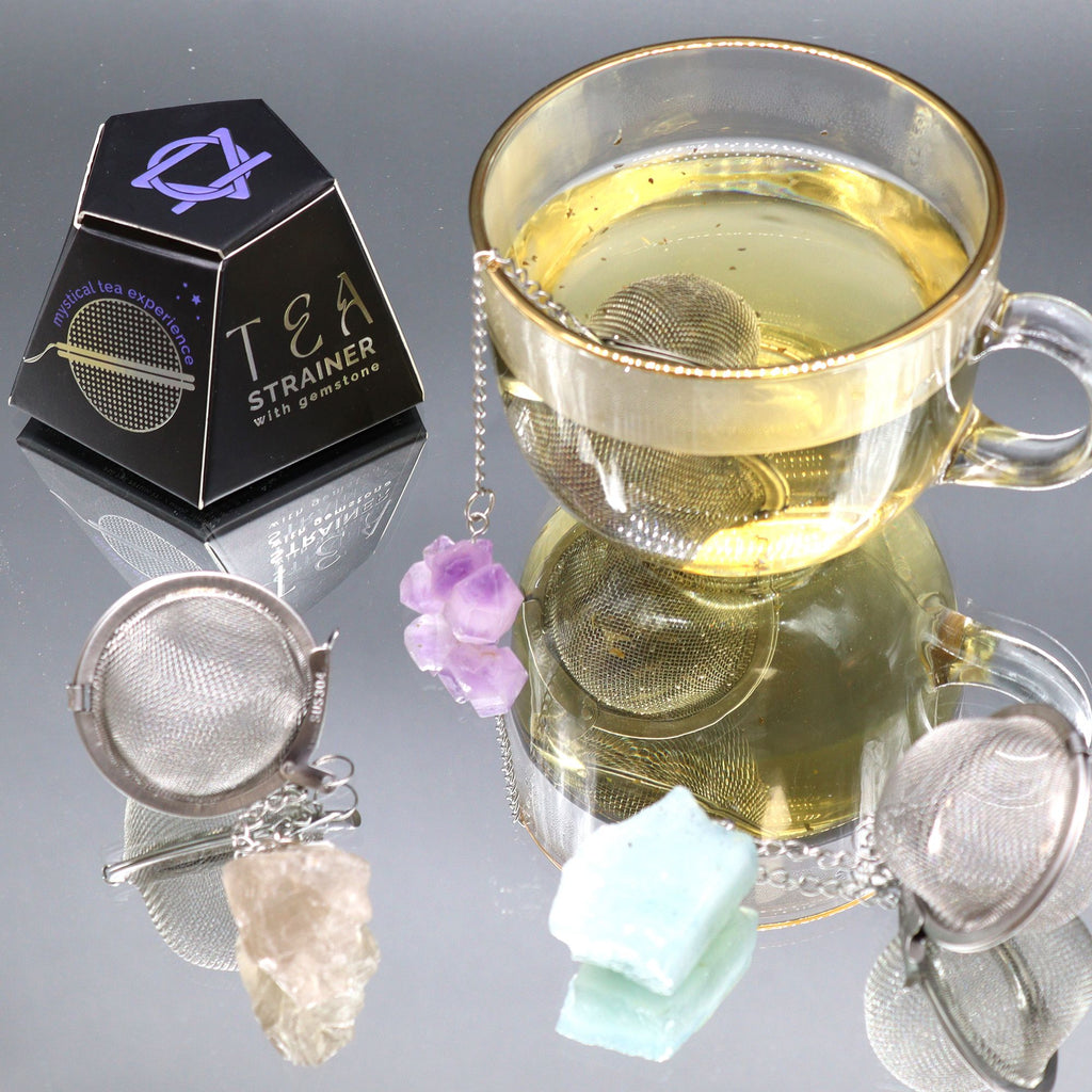 Tea strainer with tea leaves in a glass of tea on a reflective surface.