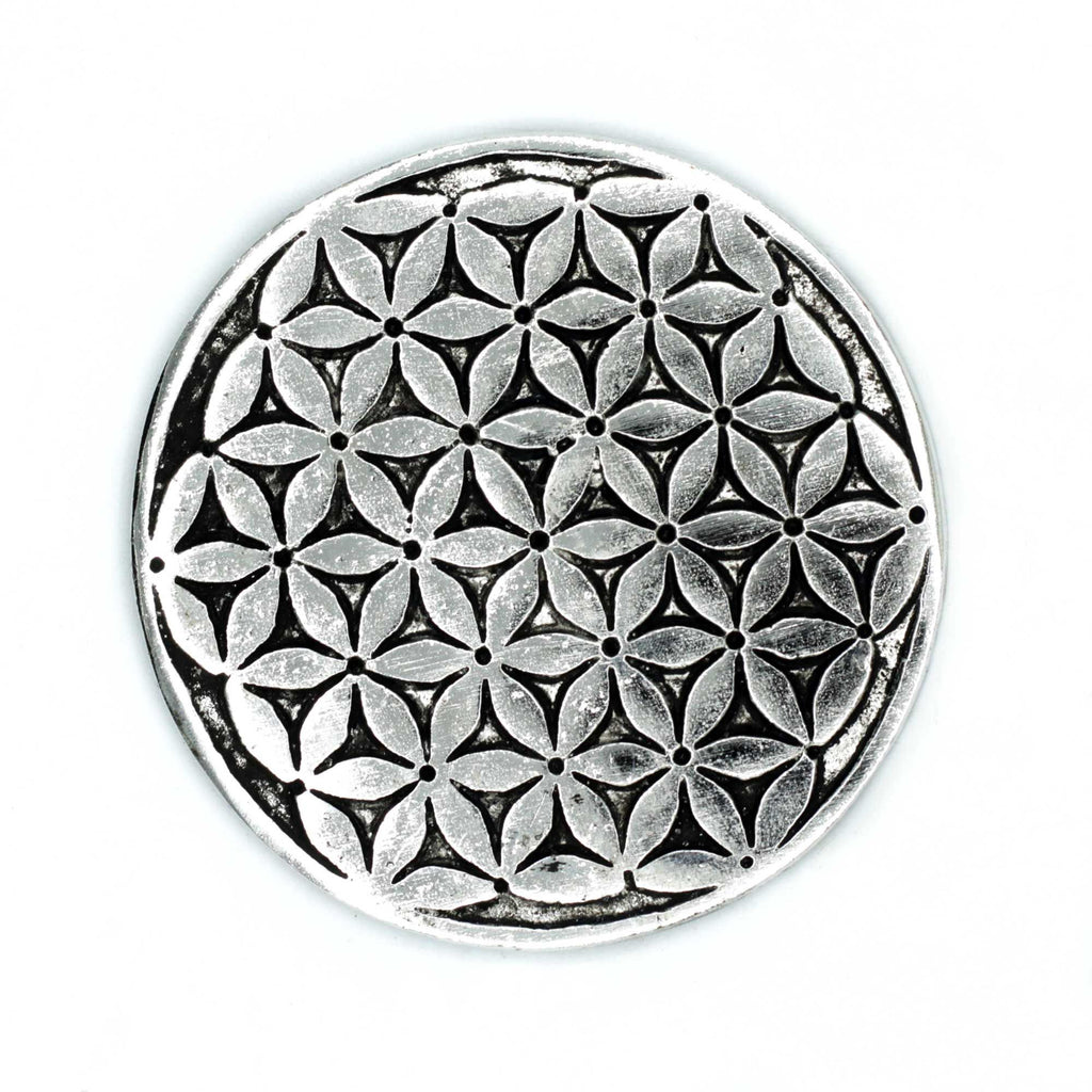Circular metal object with a geometric flower pattern on a white background