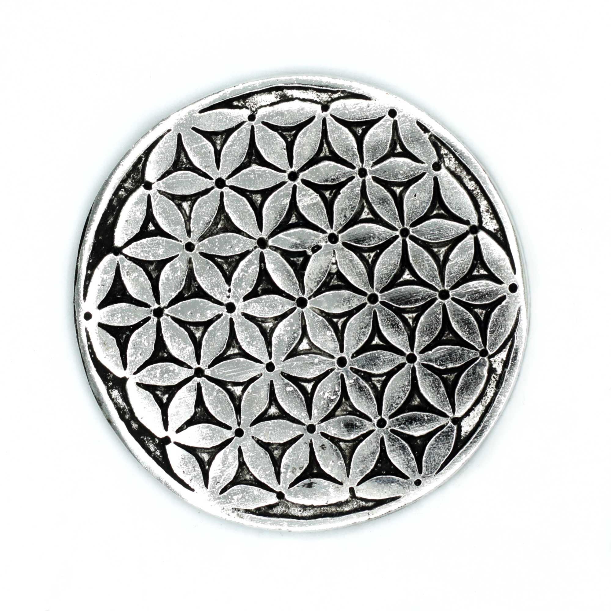 Circular metal object with a geometric flower pattern on a white background