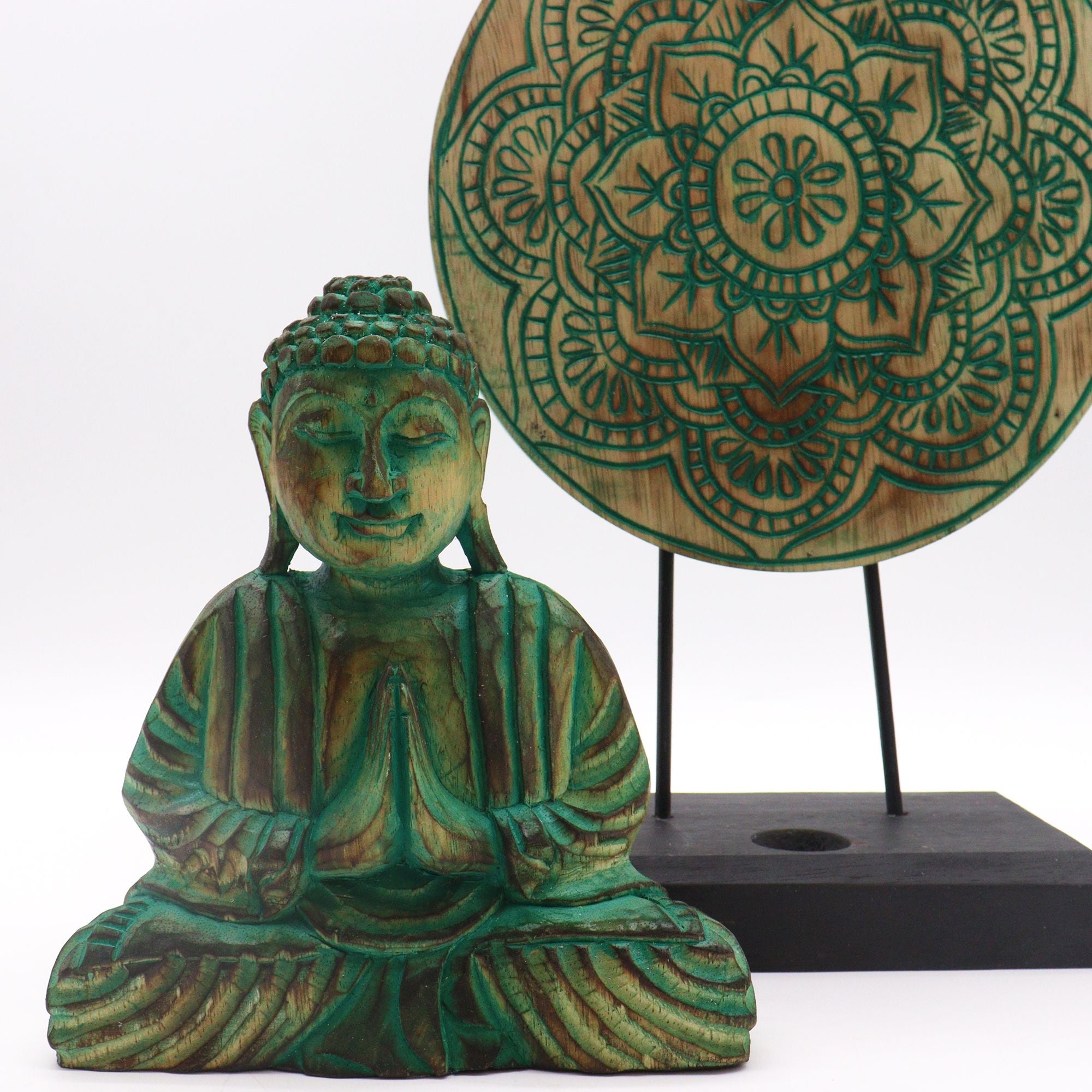 Green Buddha statue and wooden mandala on a white background