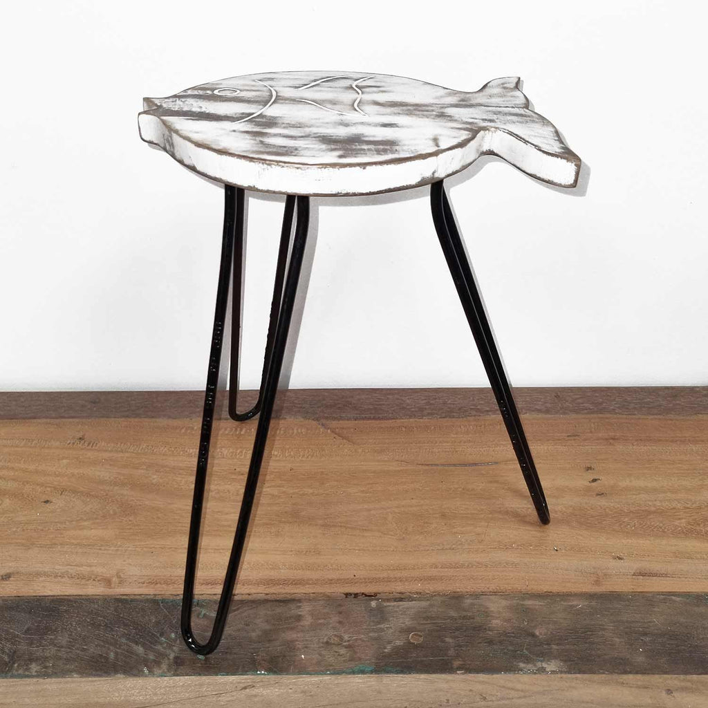 Small round table with a fish-shaped top on a wooden floor.