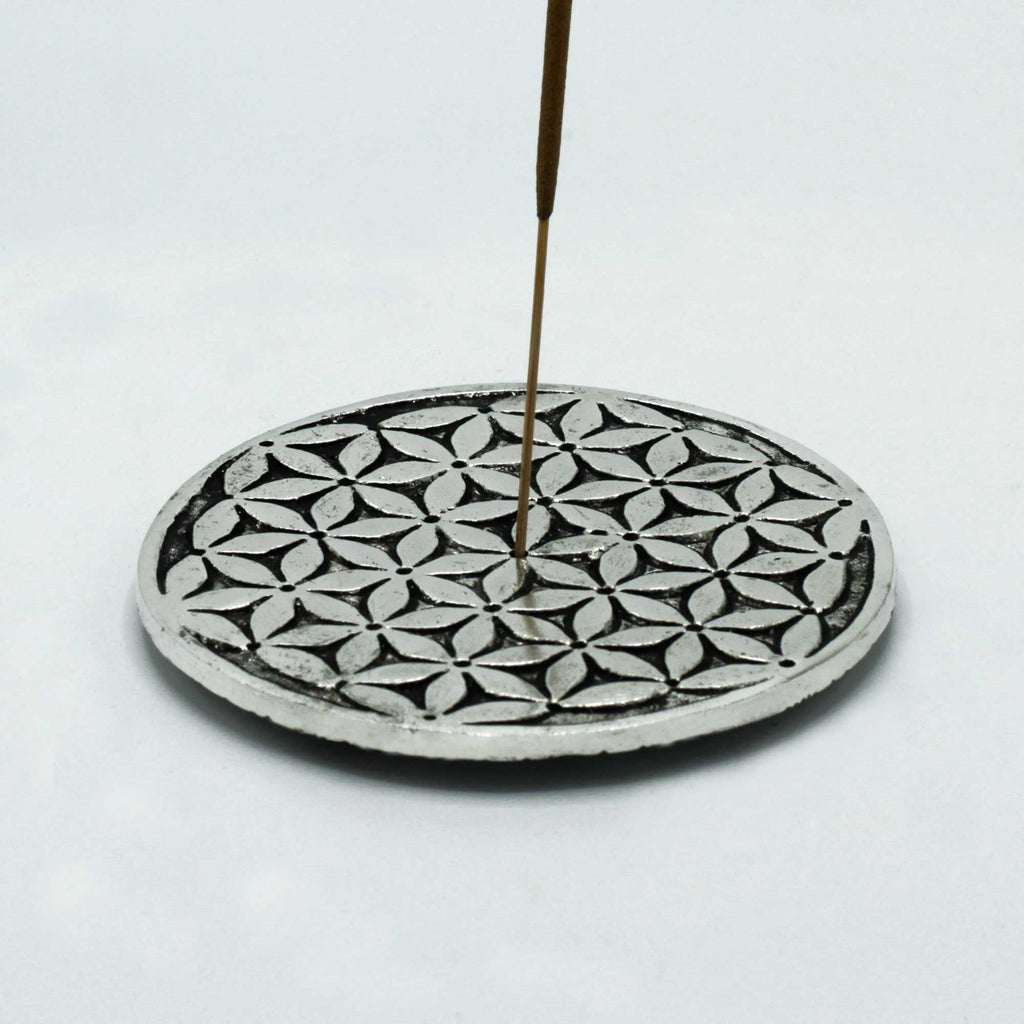 Decorative incense holder with a patterned base and a single incense stick on a white background