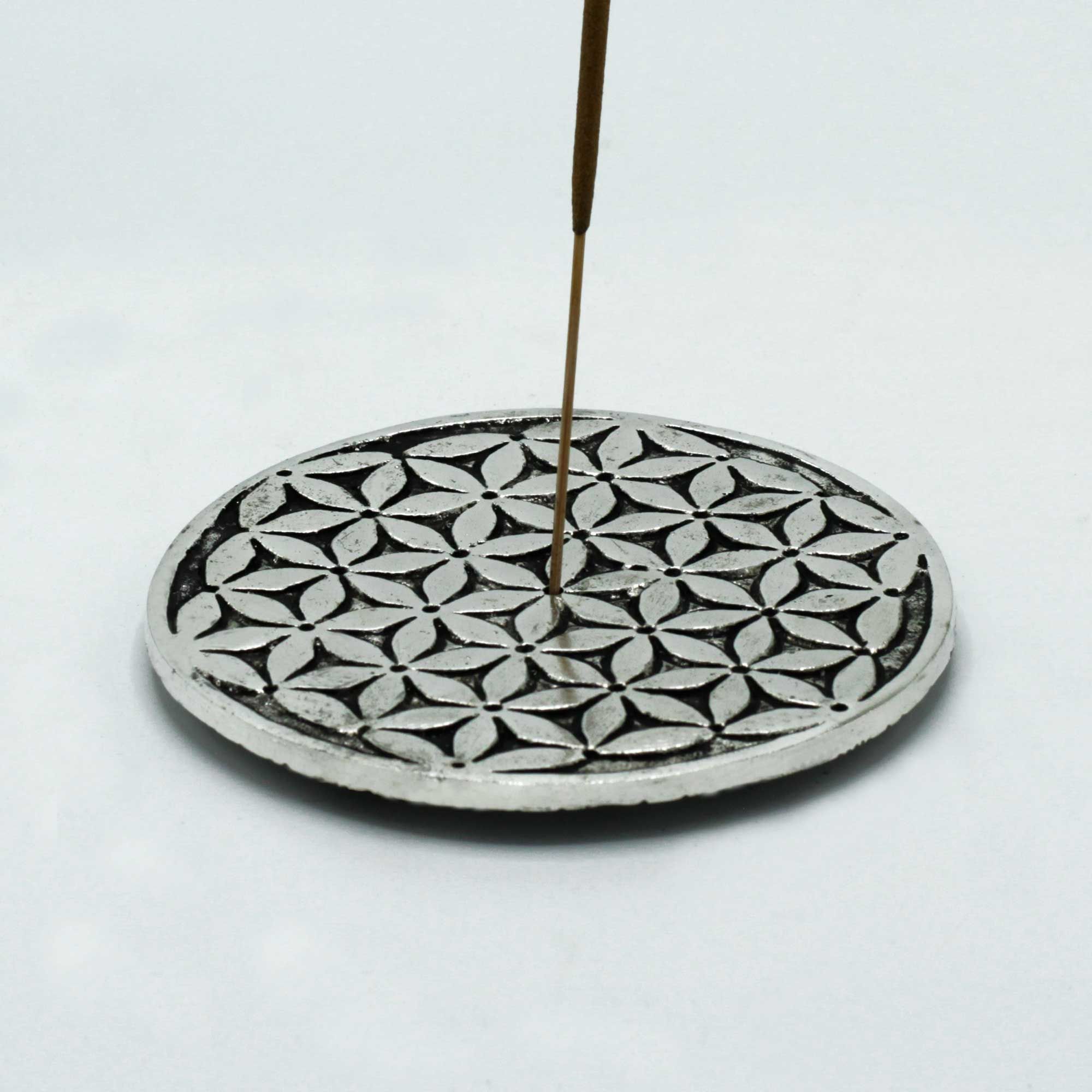 Decorative incense holder with a patterned base and a single incense stick on a white background