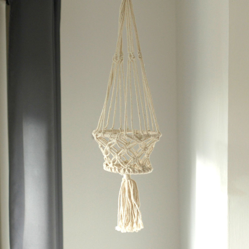 Macrame plant hanger with tassel on a neutral background