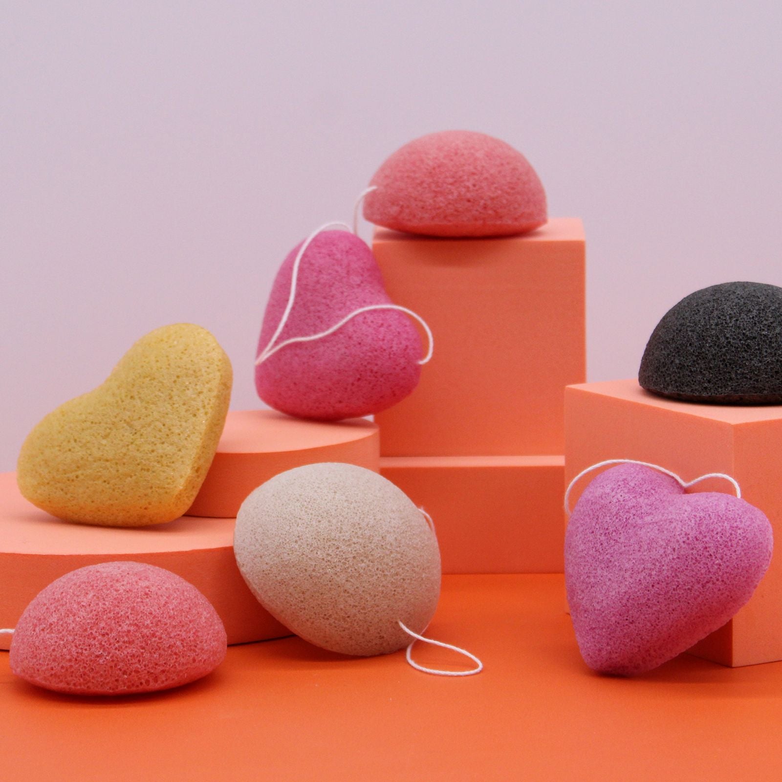 Set of colorful konjac sponges on an orange and pink geometric background