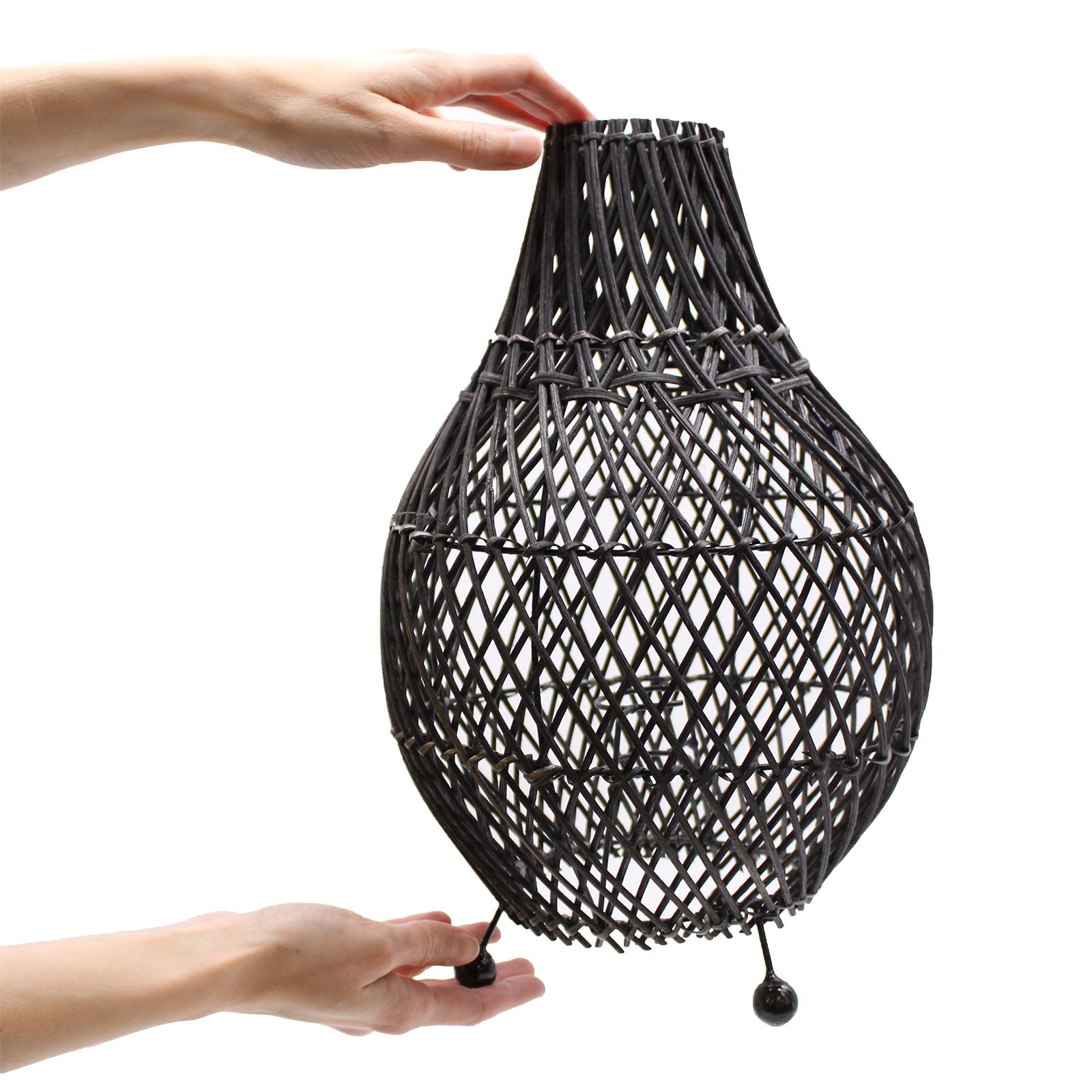 Black woven pendant light held by a hand on a white background