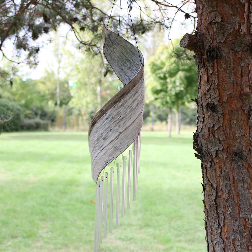 Wooden wind chime hanging from a tree in a park setting