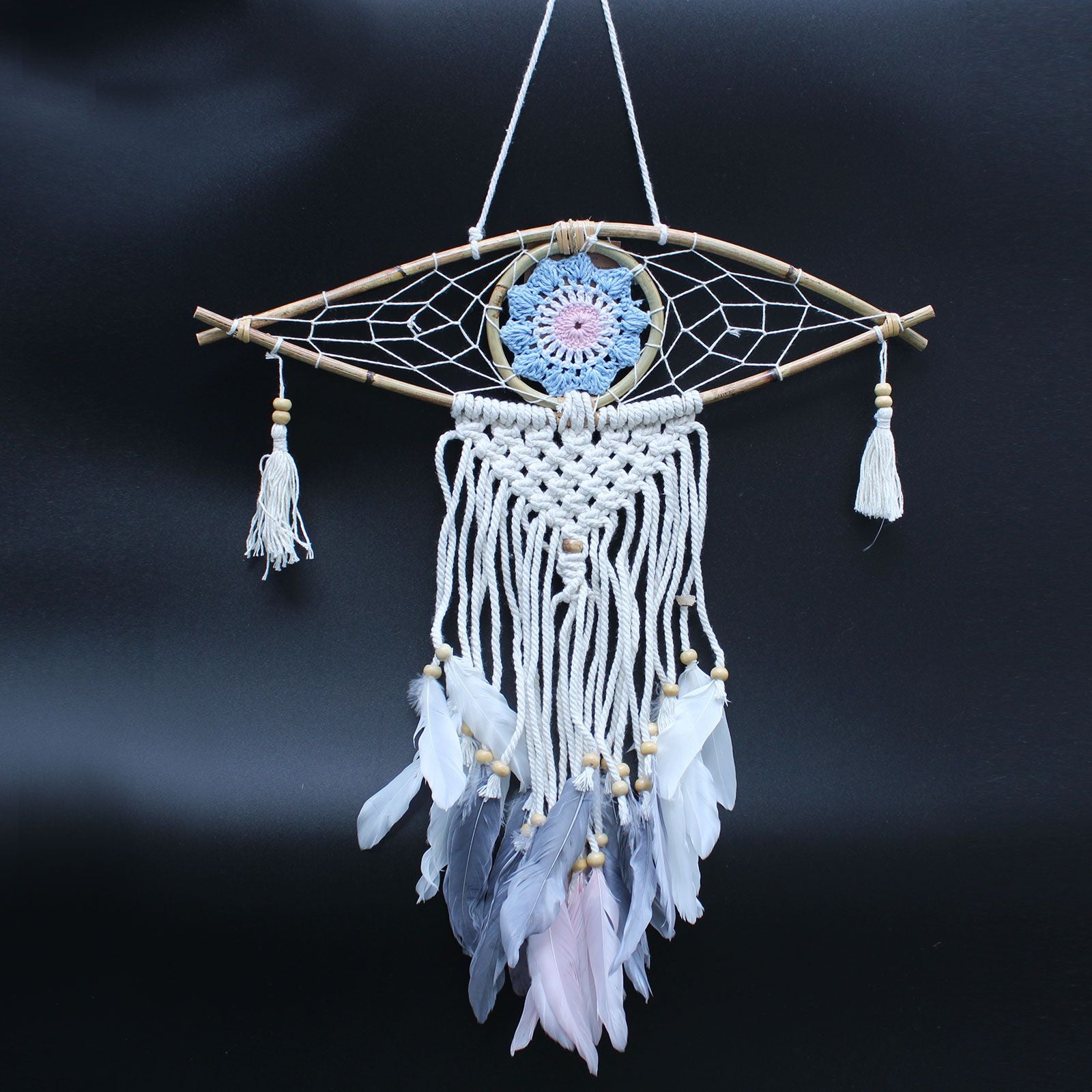 Decorative dreamcatcher with feathers and beads on a dark background