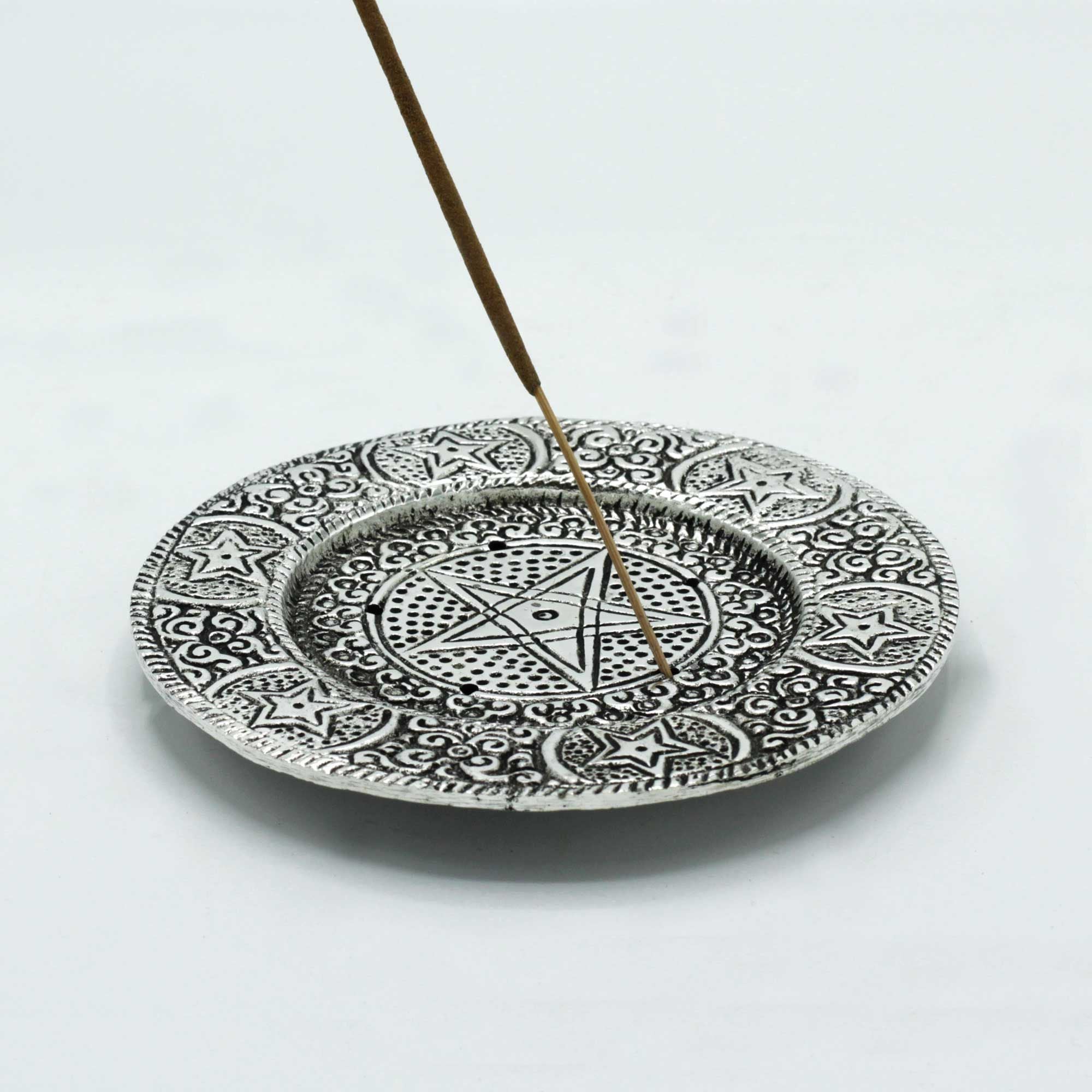 Decorative plate with black patterns and an incense stick on a white background