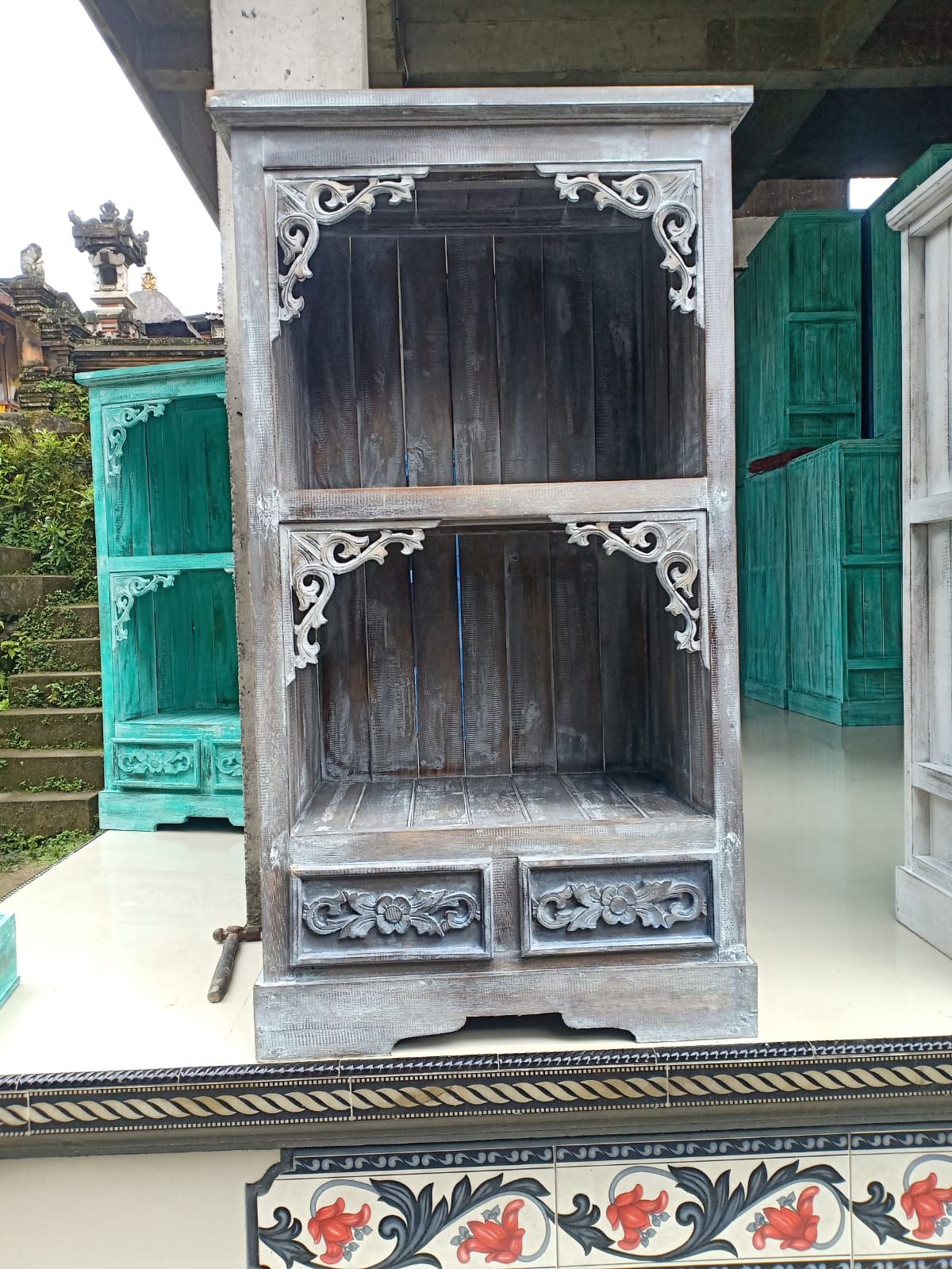 Decorative wooden shelf with intricate carvings in an outdoor setting