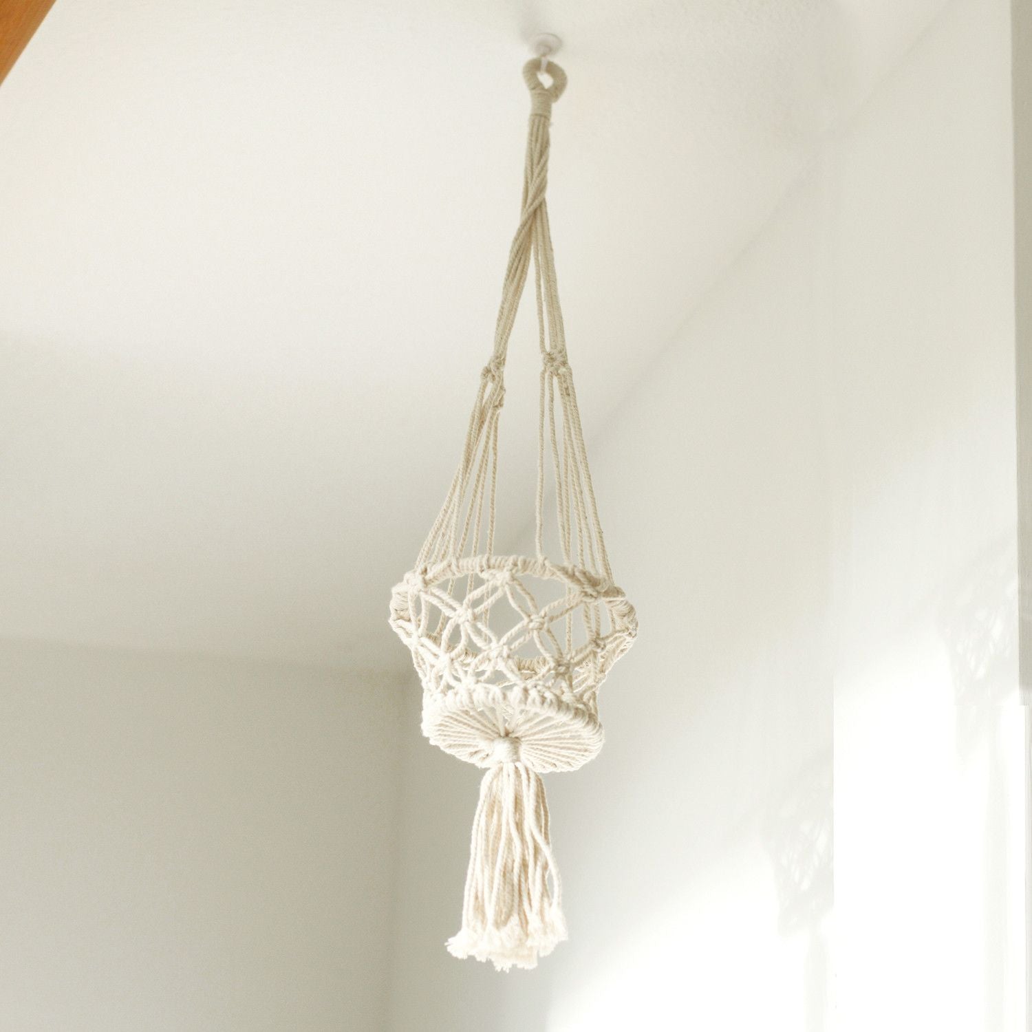 Macrame plant hanger hanging against a plain wall
