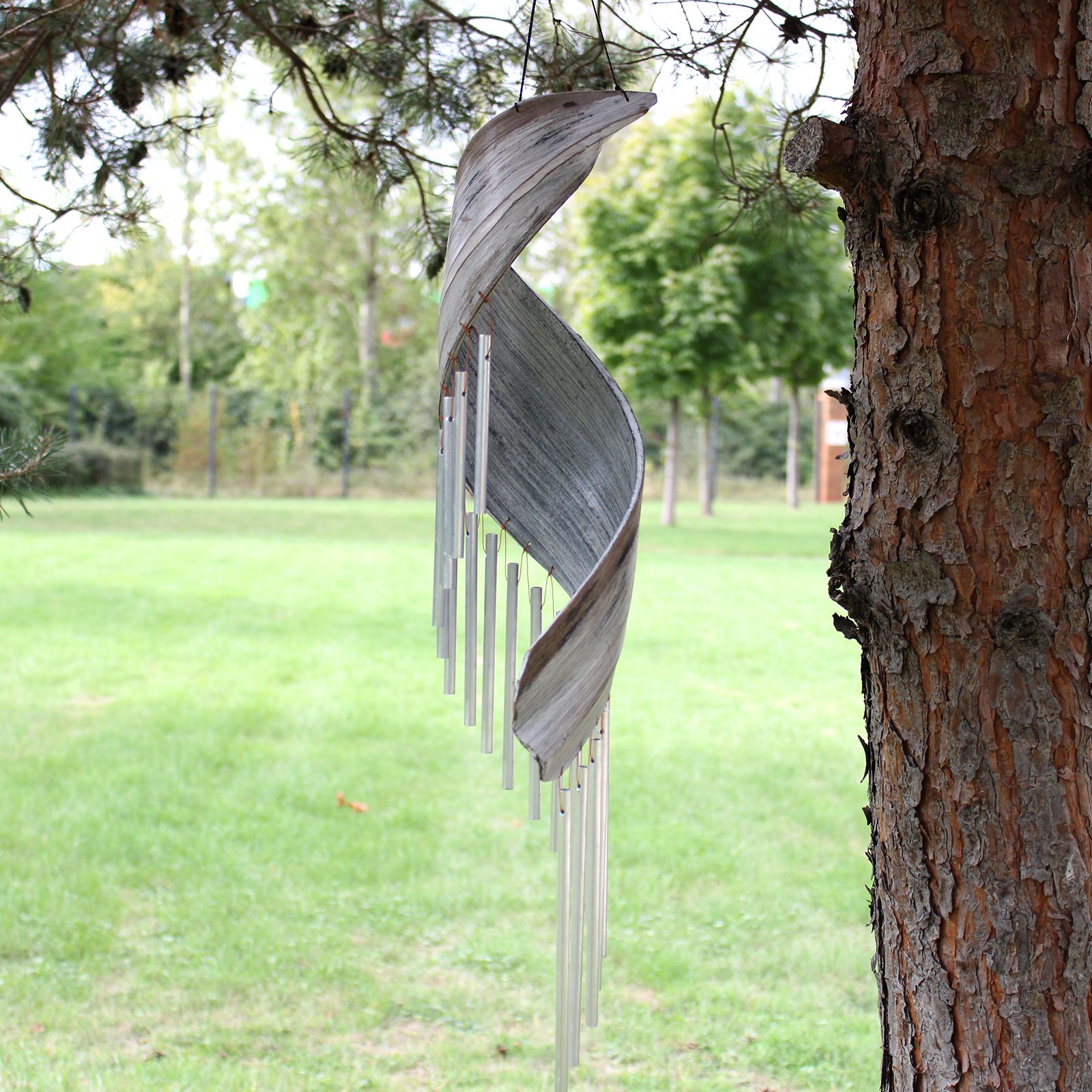 Decorative wind chime hanging from a tree in a park setting