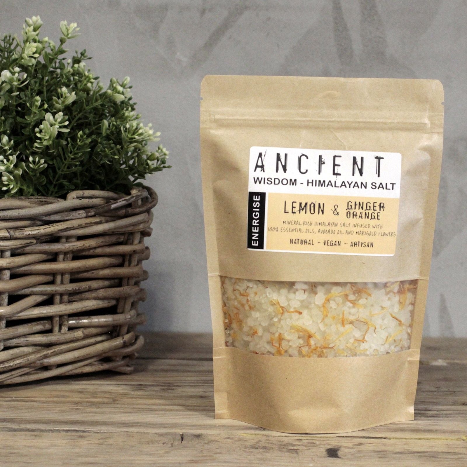 Packaged lemon and ginger Himalayan salt on a wooden surface with a plant in the background