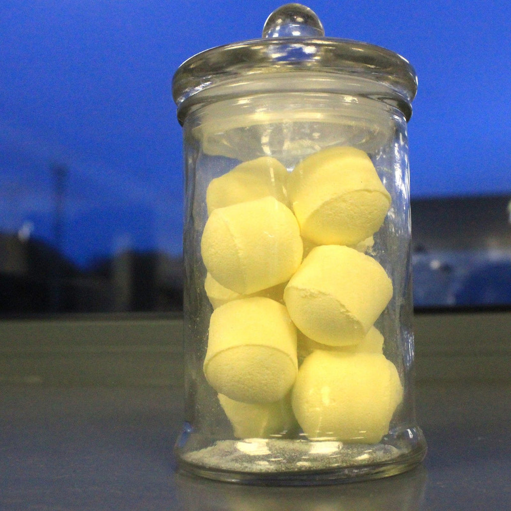 Clear glass jar filled with yellow balls against a blue background