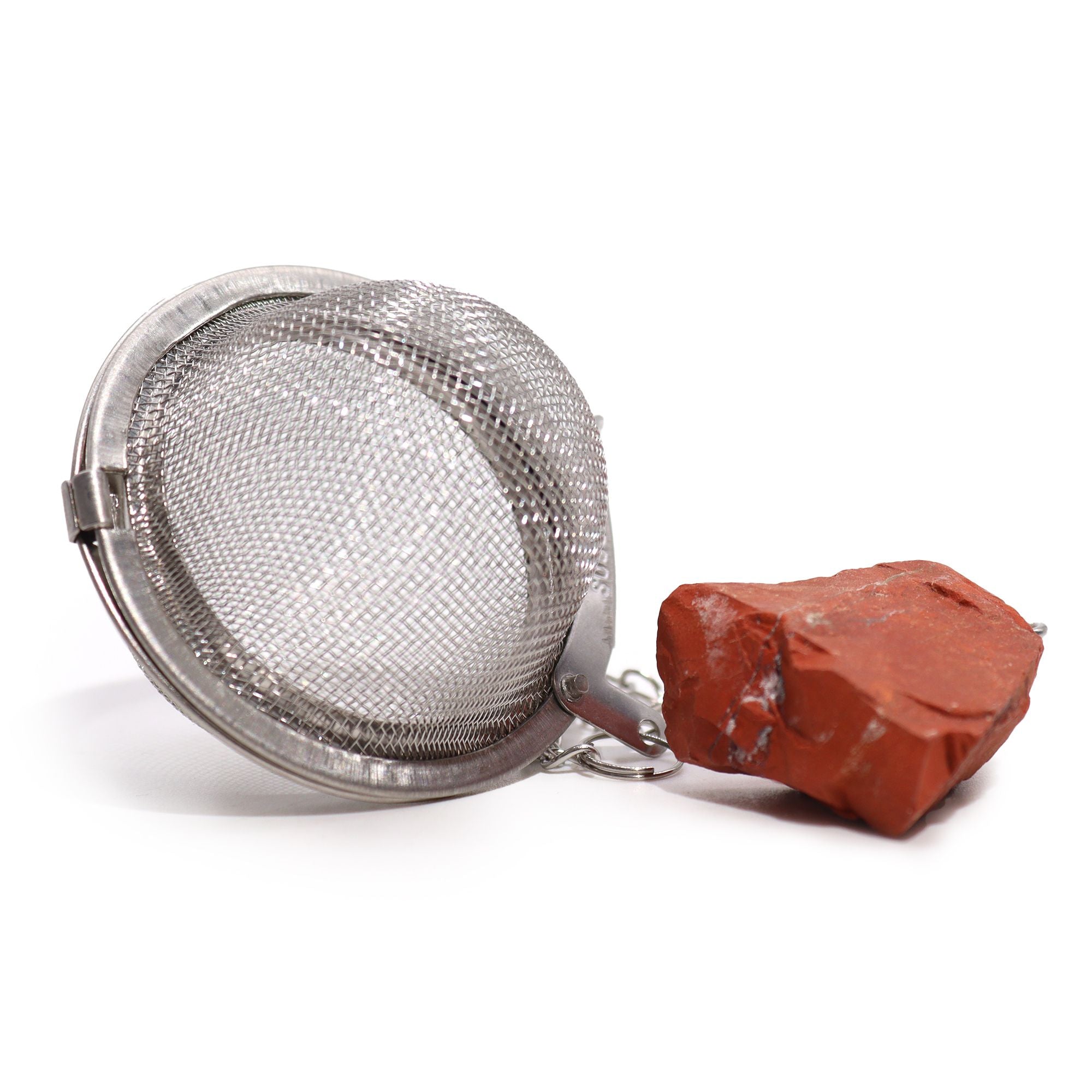 Metal mesh tea ball and red stone on a white background