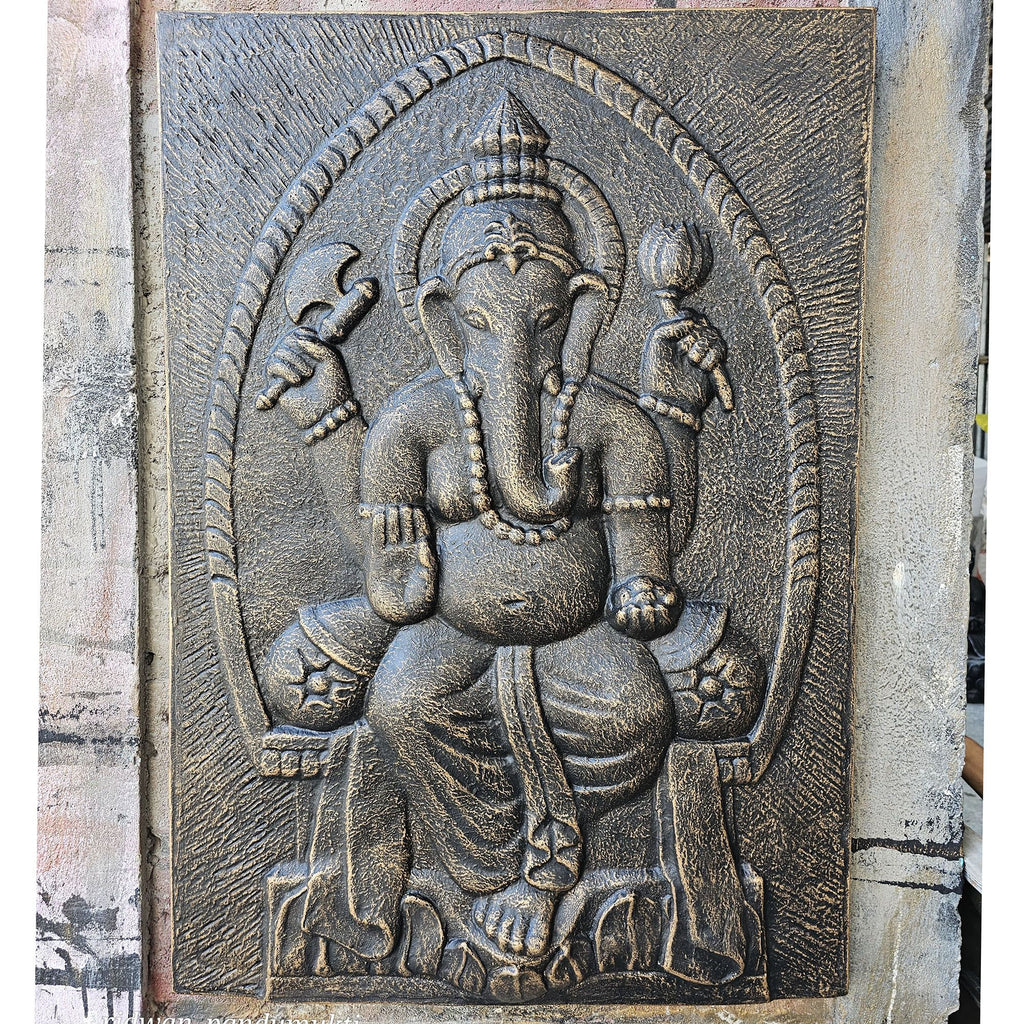 Carved stone panel of a deity with intricate details on a textured wall.