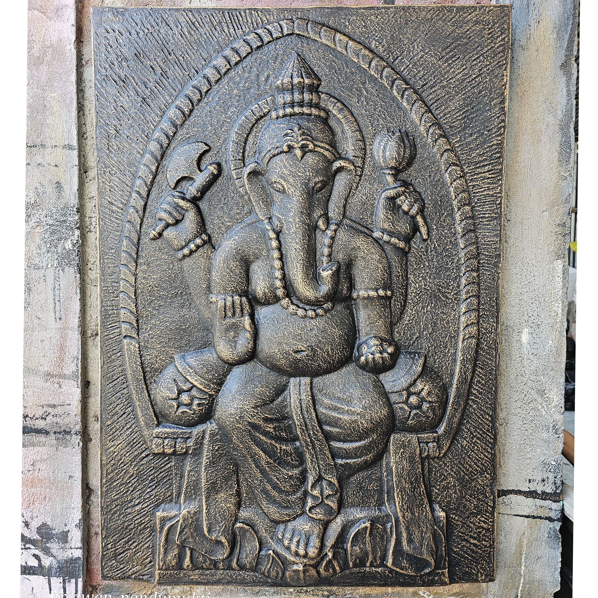 Carved stone panel of a deity with intricate details on a textured wall.