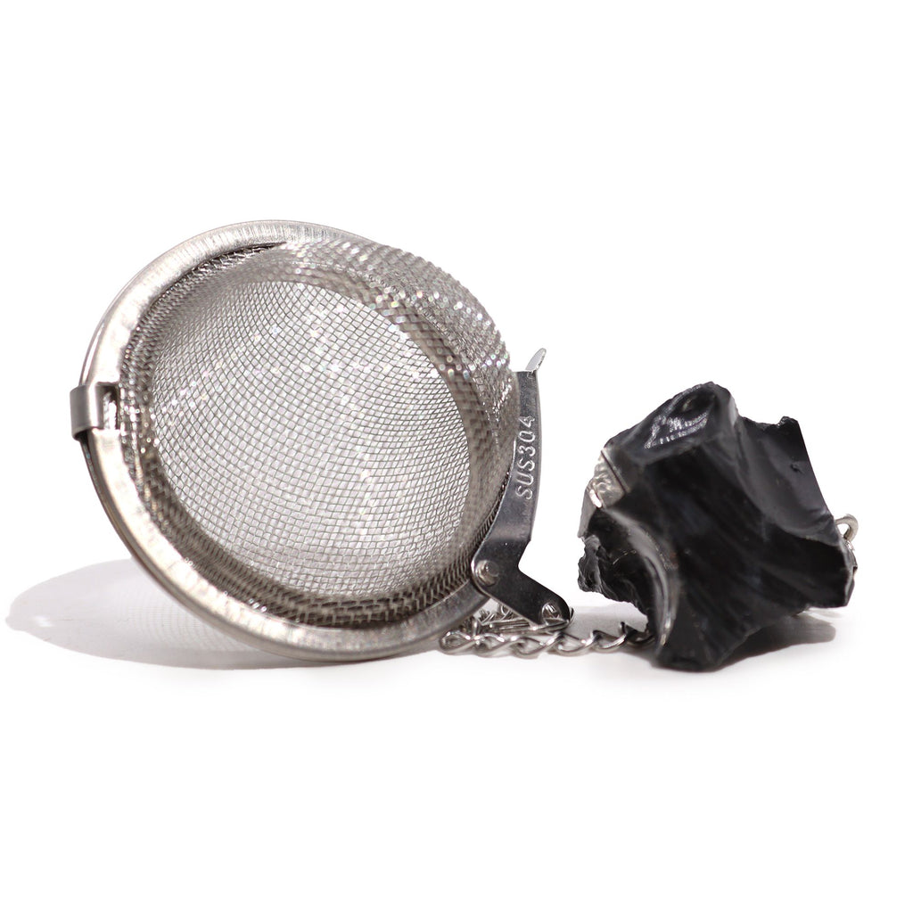 Metallic tea ball infuser with a black handle on a white background