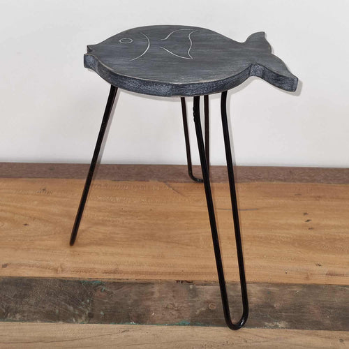 Fish-shaped side table with black hairpin legs on a wooden floor.
