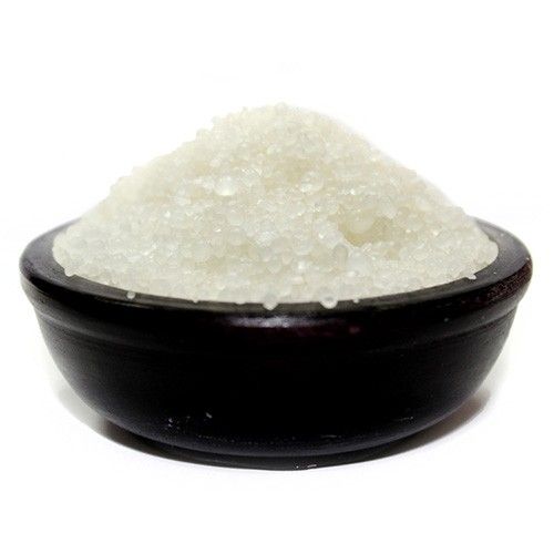 Black bowl filled with white sugar on a white background