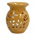 Yellow ceramic oil burner with perforated design on a white background