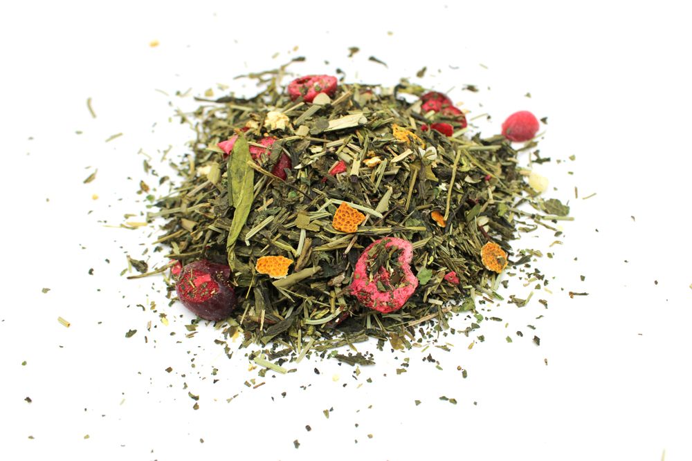 Pile of green tea leaves with red berries and orange flowers on a white background