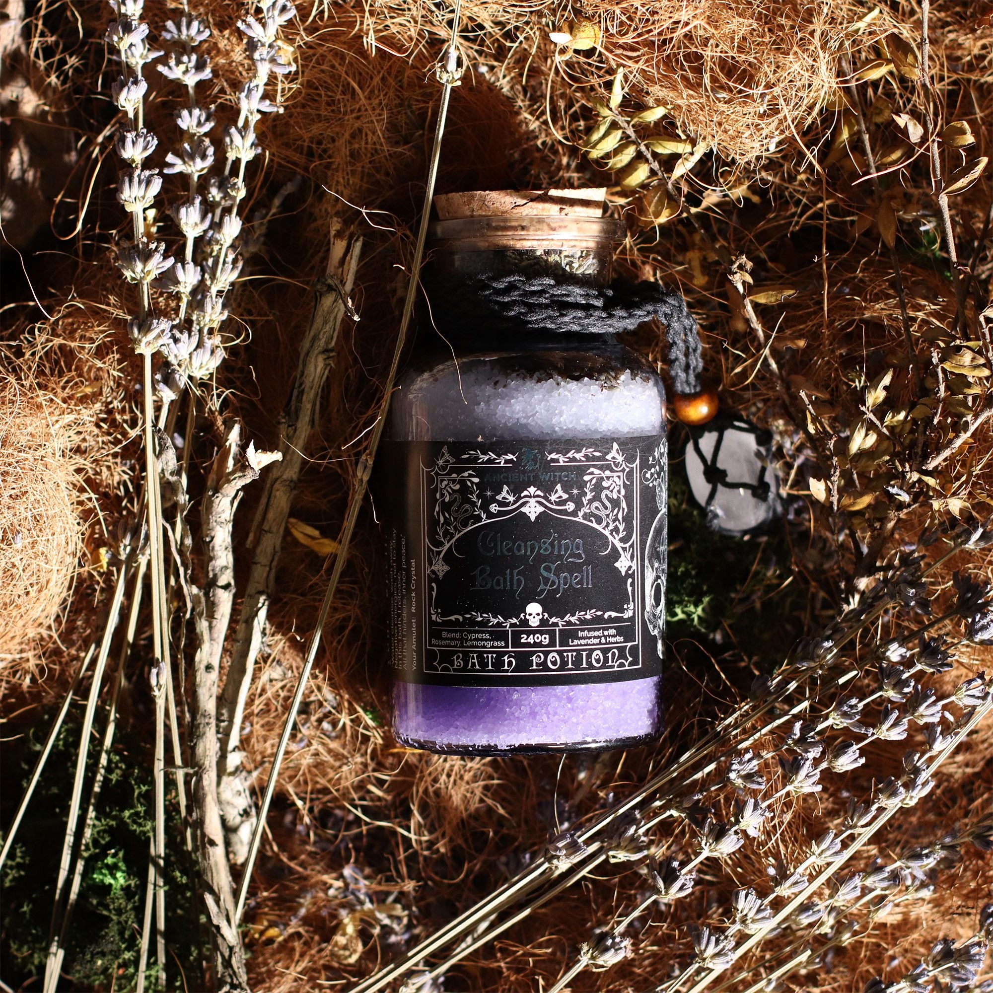 Purple potion bottle with decorative label on a bed of hay and herbs