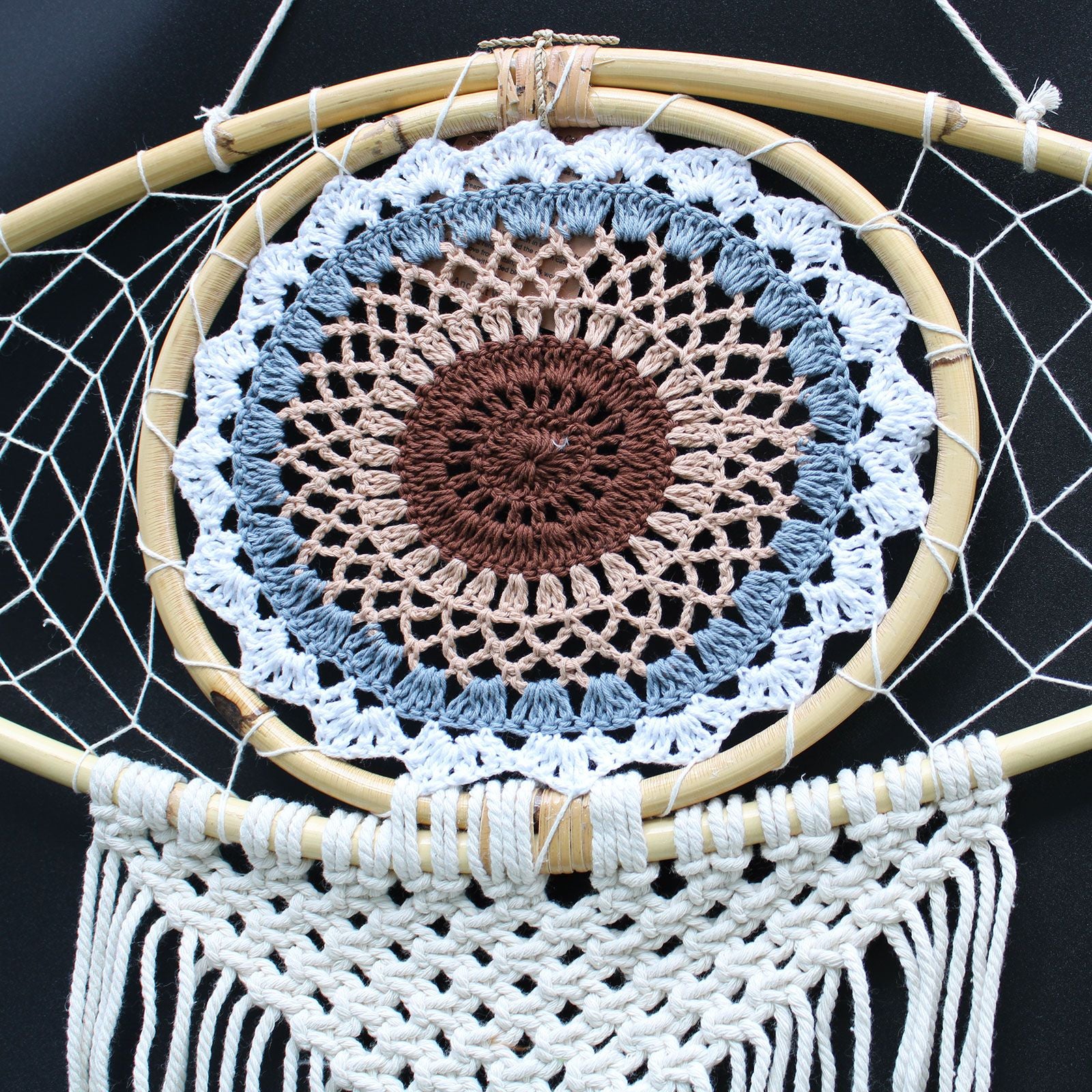 Crocheted dreamcatcher with concentric circles and white netting on a black background