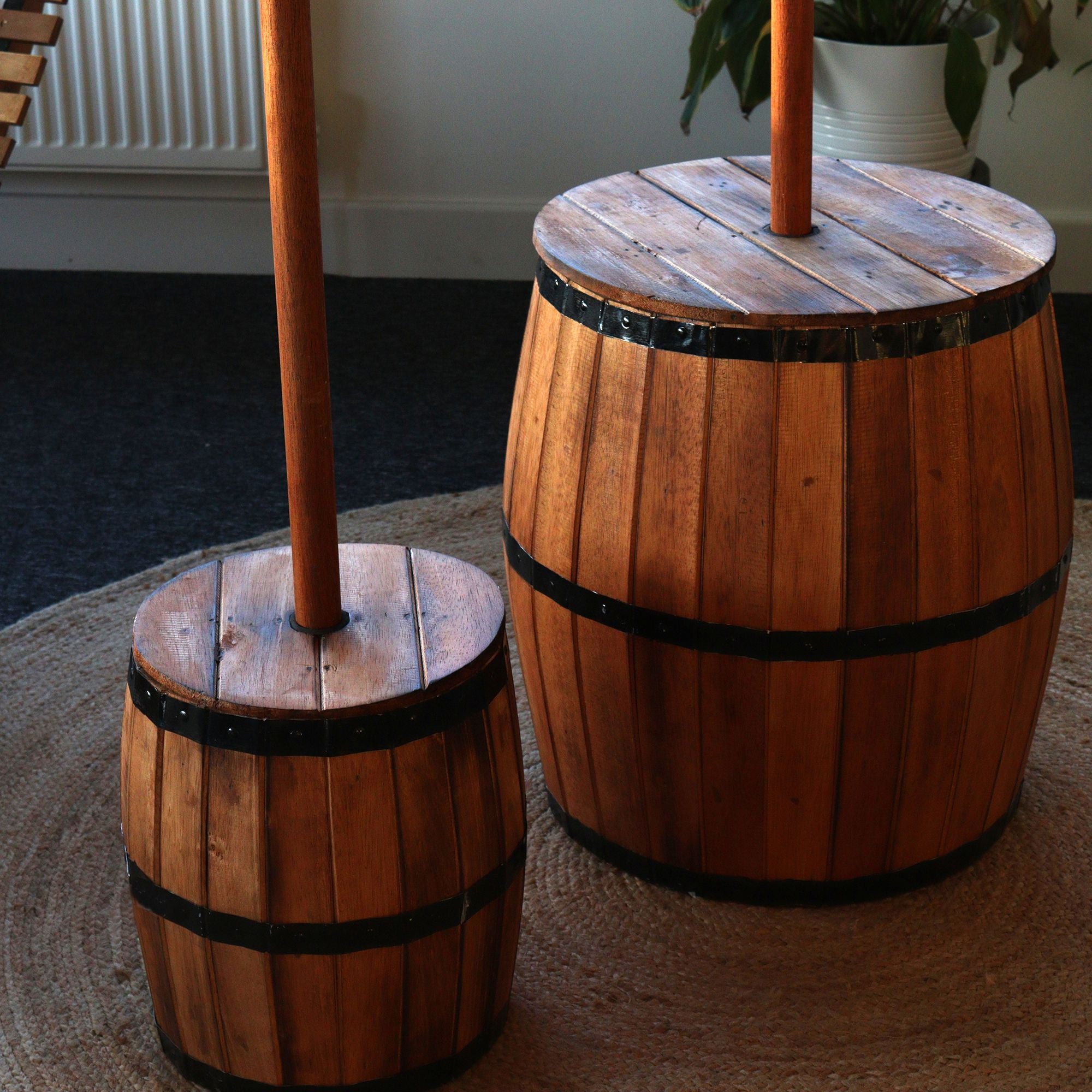 Two wooden barrel tables with umbrella stands on a carpeted floor.