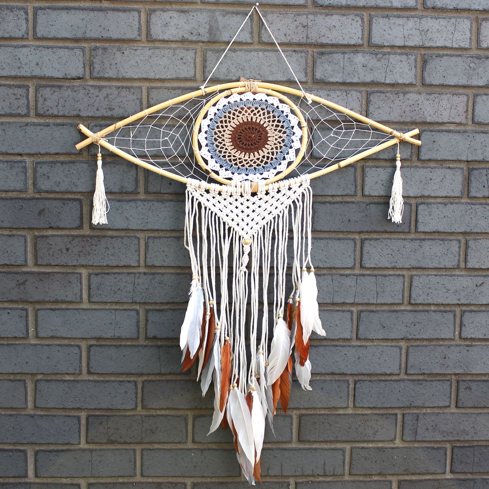 Dreamcatcher with feathers hanging on a brick wall