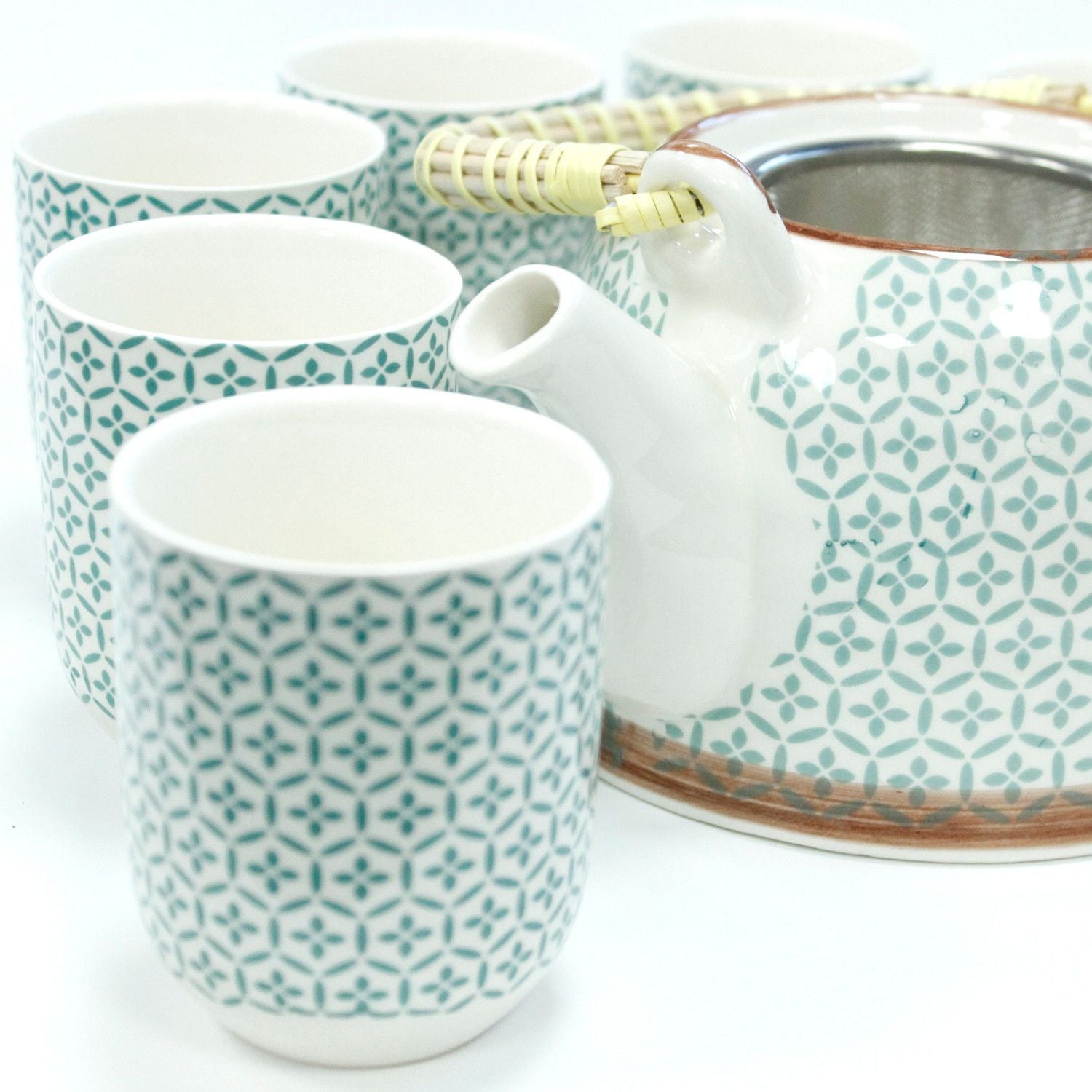 Tea set with white teapot and three matching cups featuring a green geometric pattern on a white background.