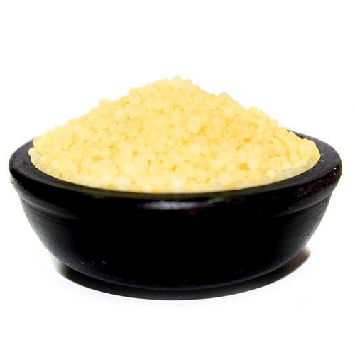 Black bowl filled with yellow granules on a white background