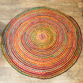 Round multicolored braided rug on a wooden floor
