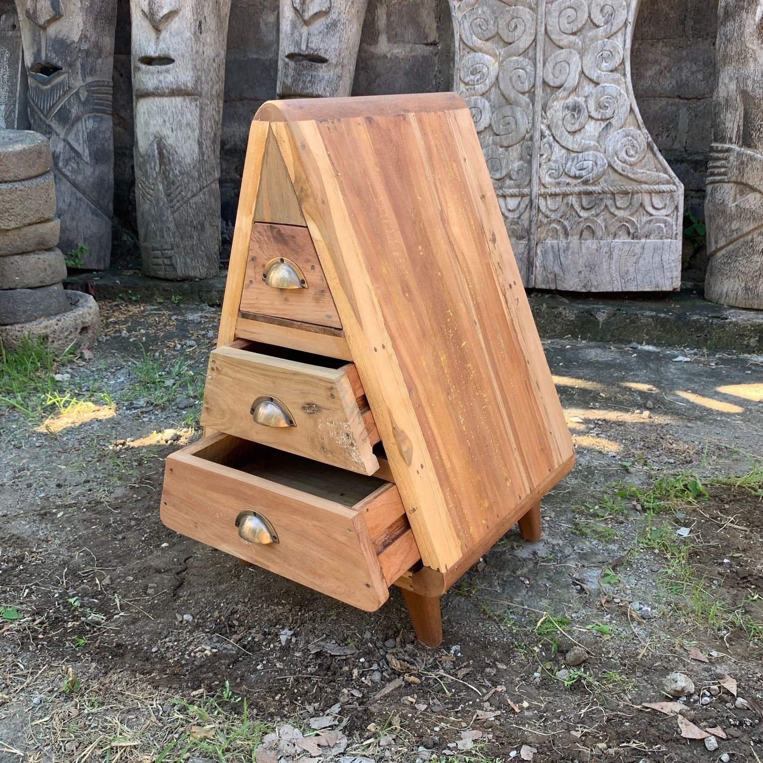 Wooden bee hive with two drawers in an outdoor setting with stone carvings.