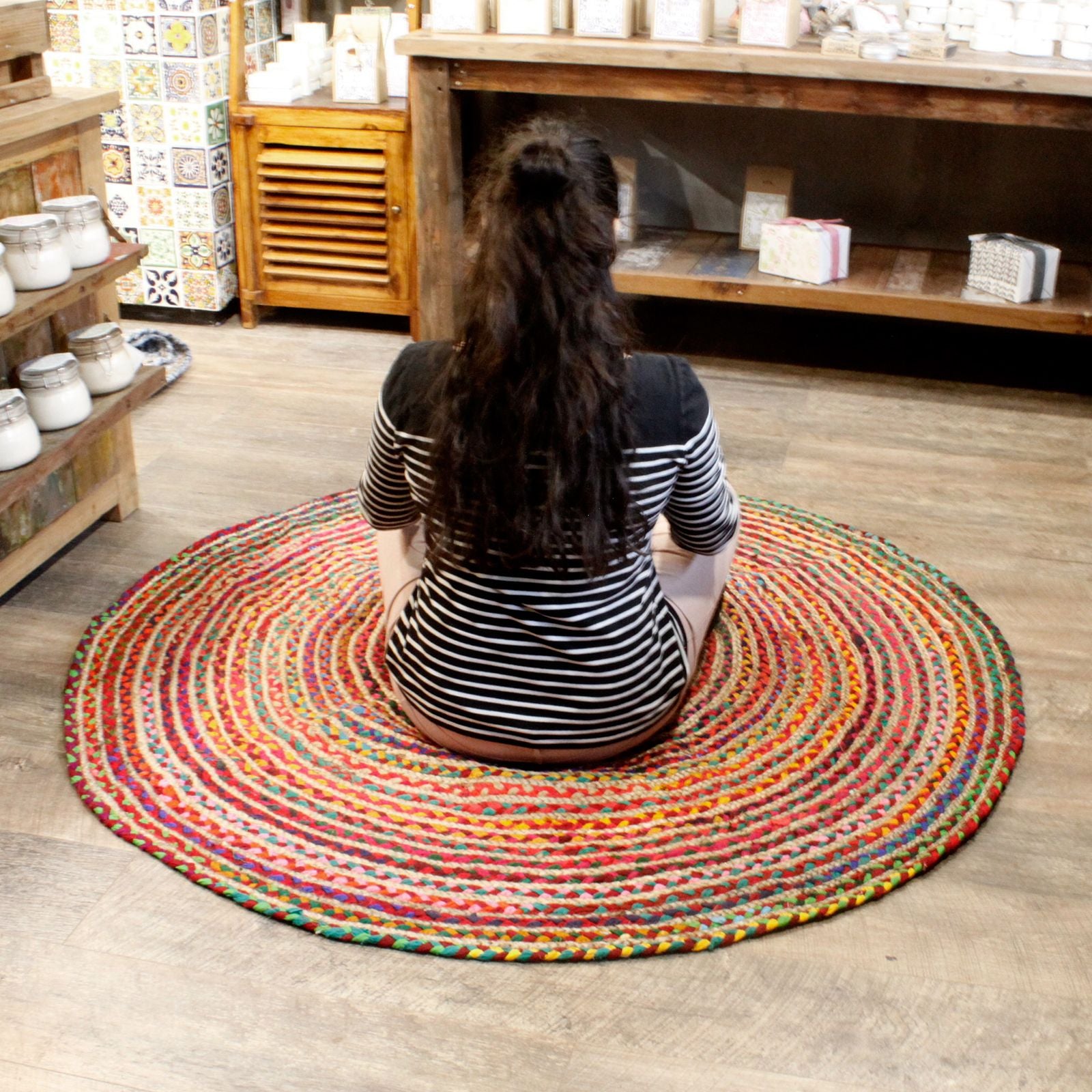 Person sitting on a colorful round rug in a store setting