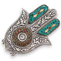 Decorative Hamsa hand with intricate patterns and colorful stones on a white background