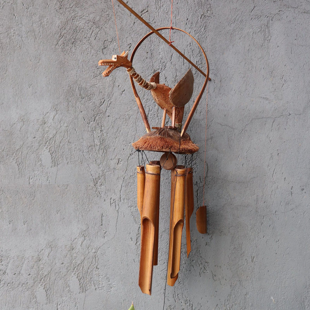 Decorative wind chime with wooden bird design on a gray wall