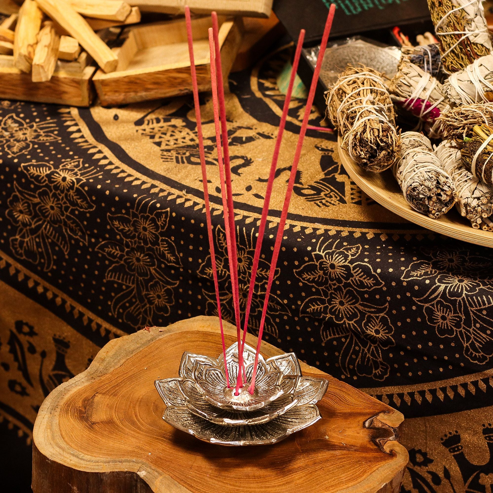 Incense sticks in a holder on a wooden surface with a patterned fabric background