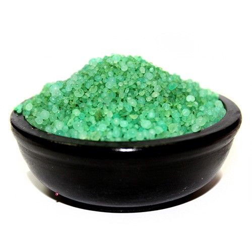 Green sand in a black bowl on a white background