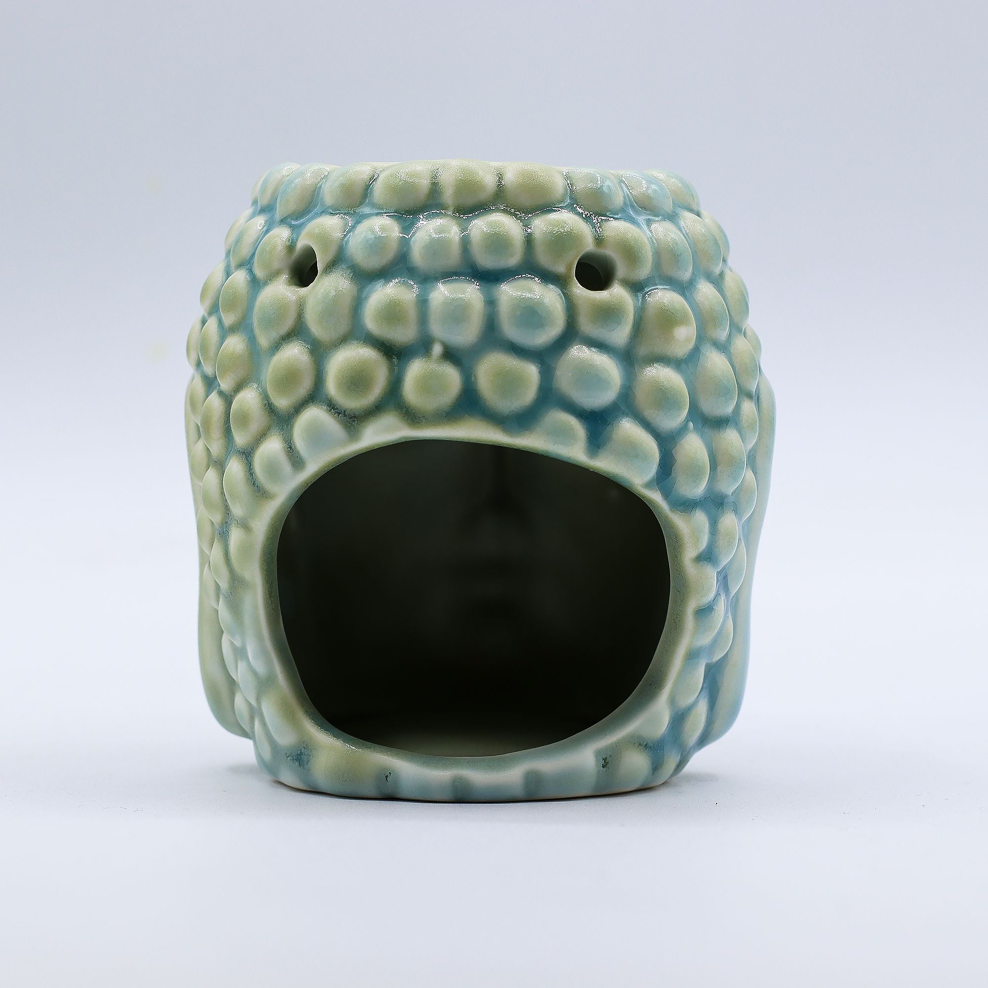 Ceramic oil burner with textured surface on a white background