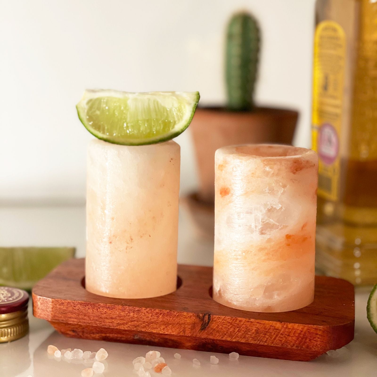 Two Himalayan salt lamps on a wooden stand with a lime wedge and blurred background.