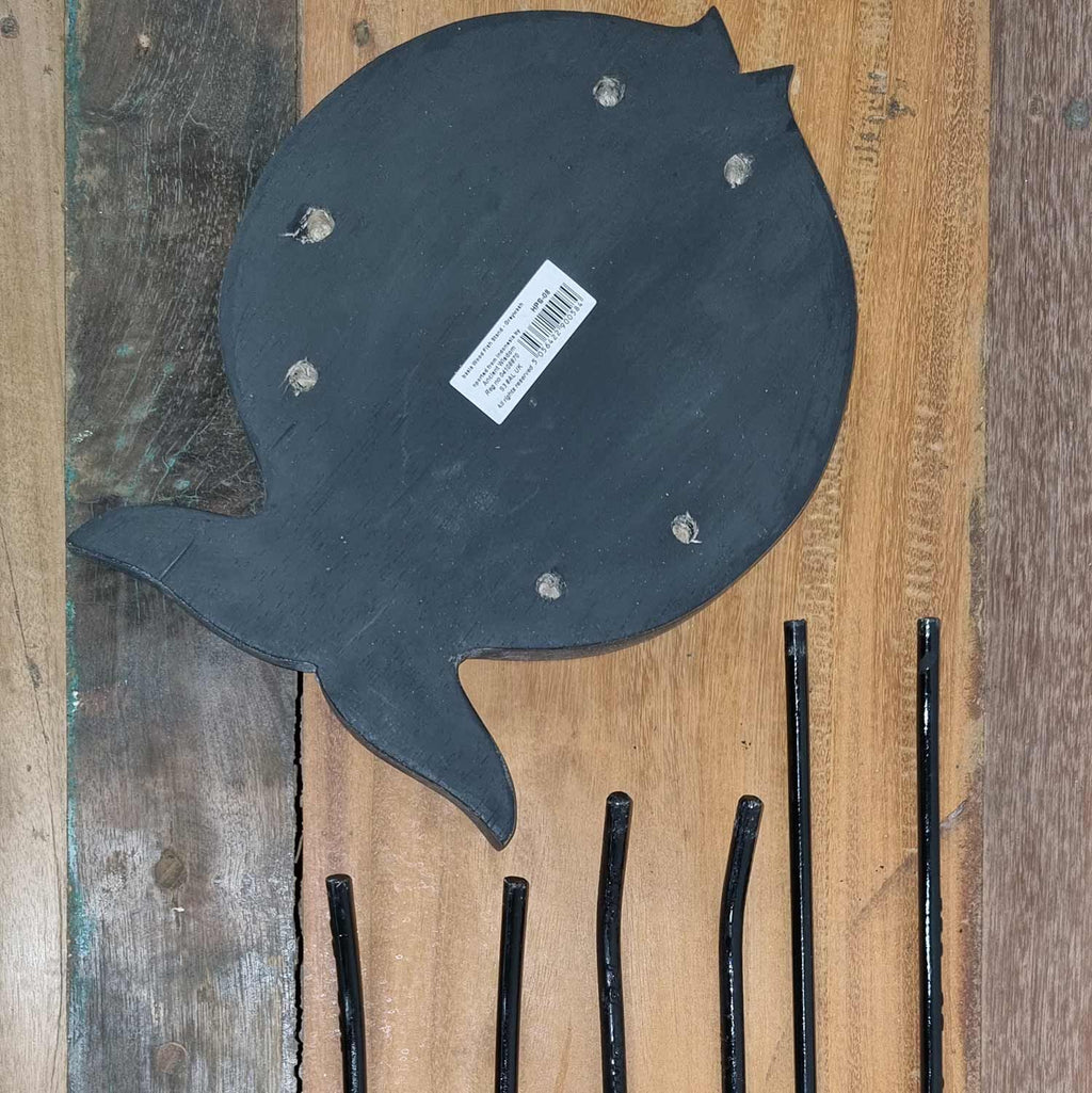 Black fish-shaped object with a label on a wooden surface