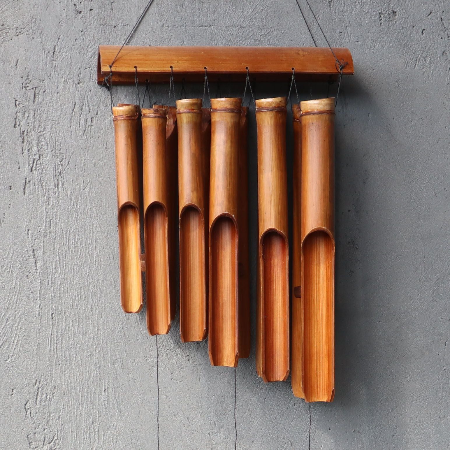 Bamboo wind chime hanging on a gray wall