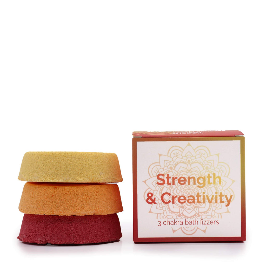 Three chakra bath fizzers stacked with their packaging on a white background