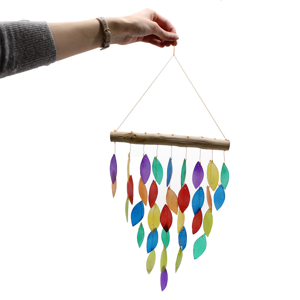 Colorful wind chime with wooden stick held by a hand on a white background