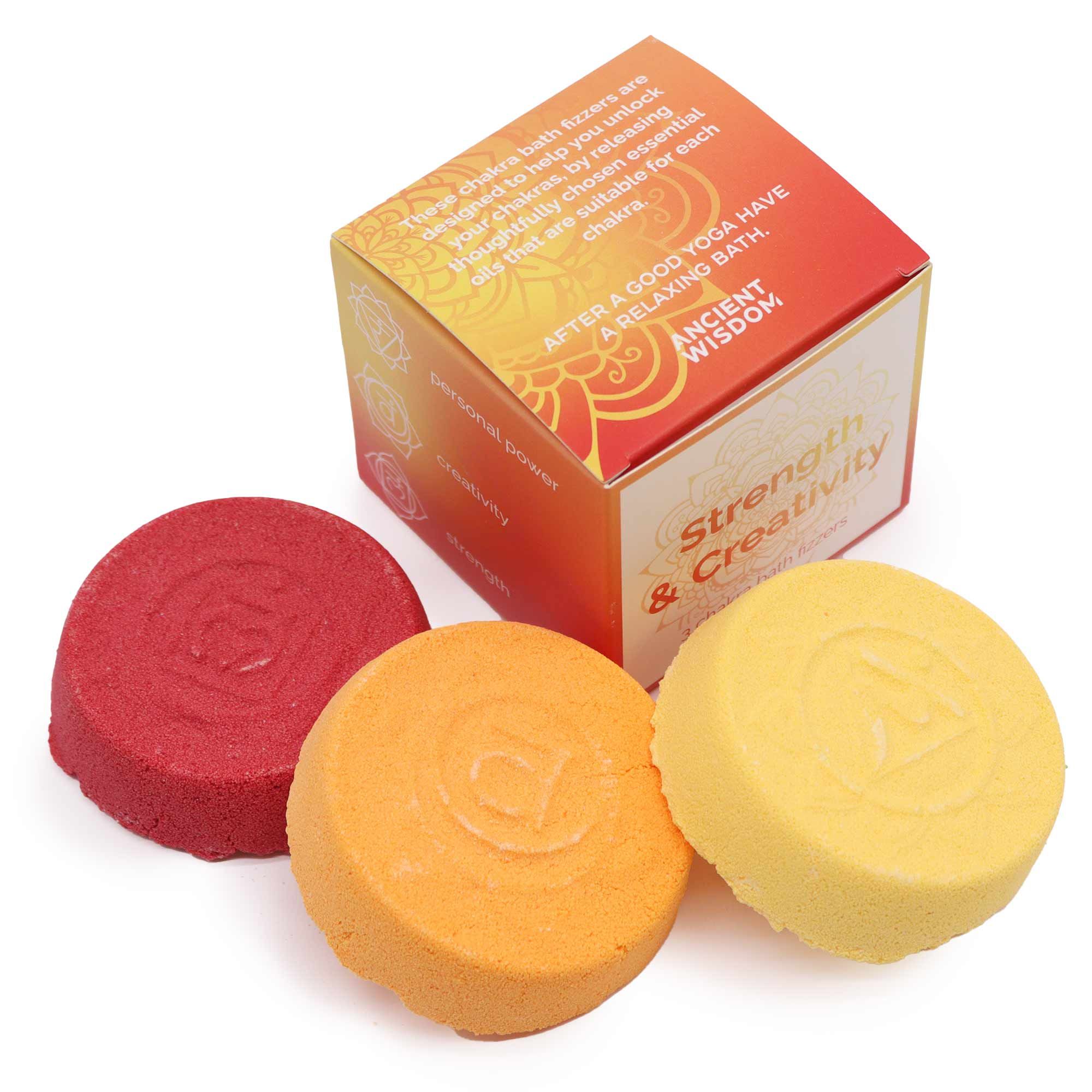 Three round bath bombs in red, orange, and yellow with a box labeled 'Strength & Creativity' on a white background.
