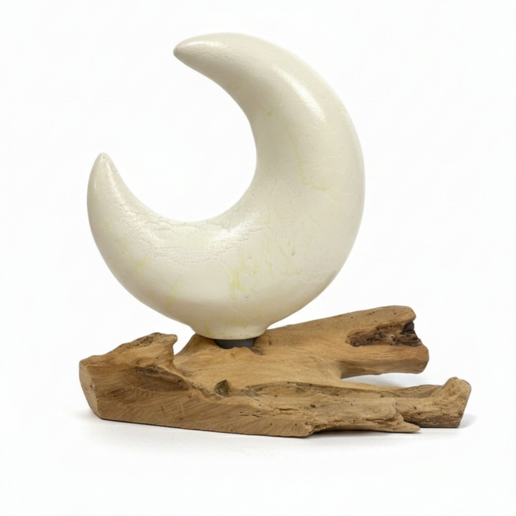 White ceramic crescent moon sculpture on a wooden base against a white background