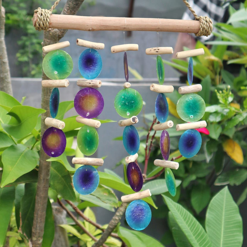 Colorful bead wind chime hanging among green leaves